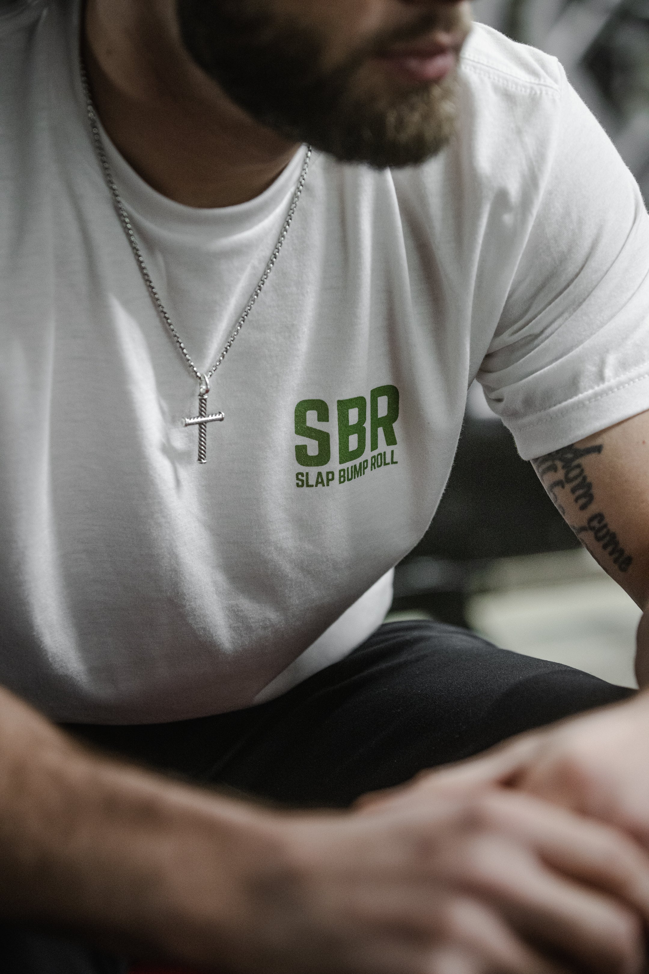 Grappler in the white Everyday Grappler tee showing the green SBR Slap Bump Roll chest mark