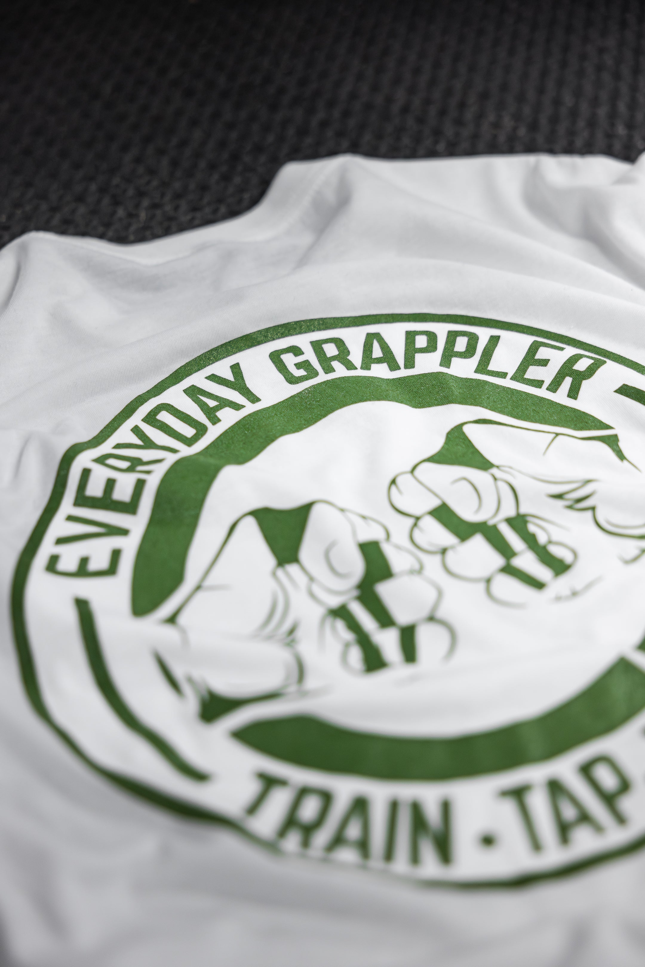 Close-up of the EVERYDAY GRAPPLER text and fist-bump graphic on the back of the white tri-blend tee