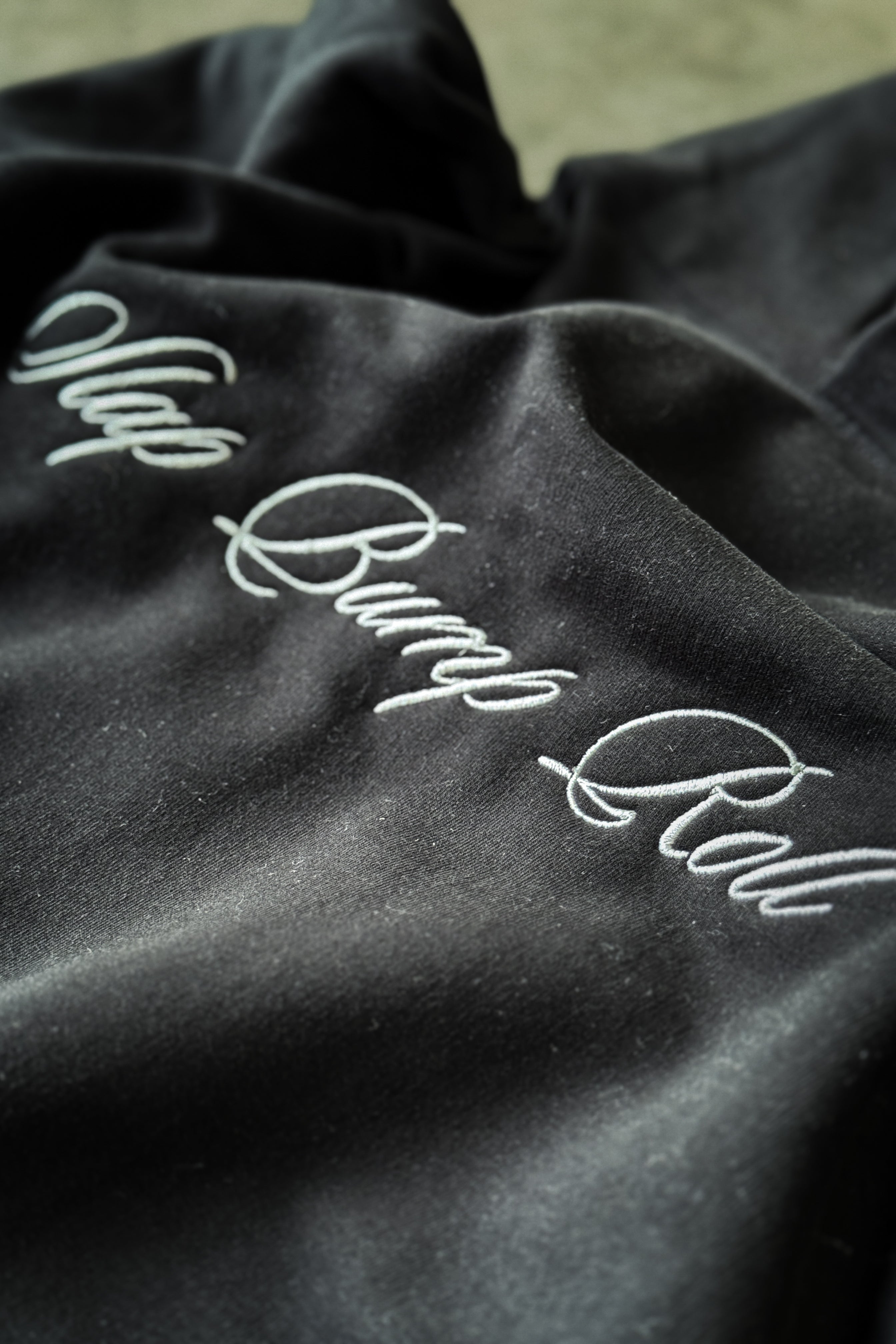 Cursive Slap Bump Roll embroidery detail on SBR Black Butter Hoodie chest, premium script branding