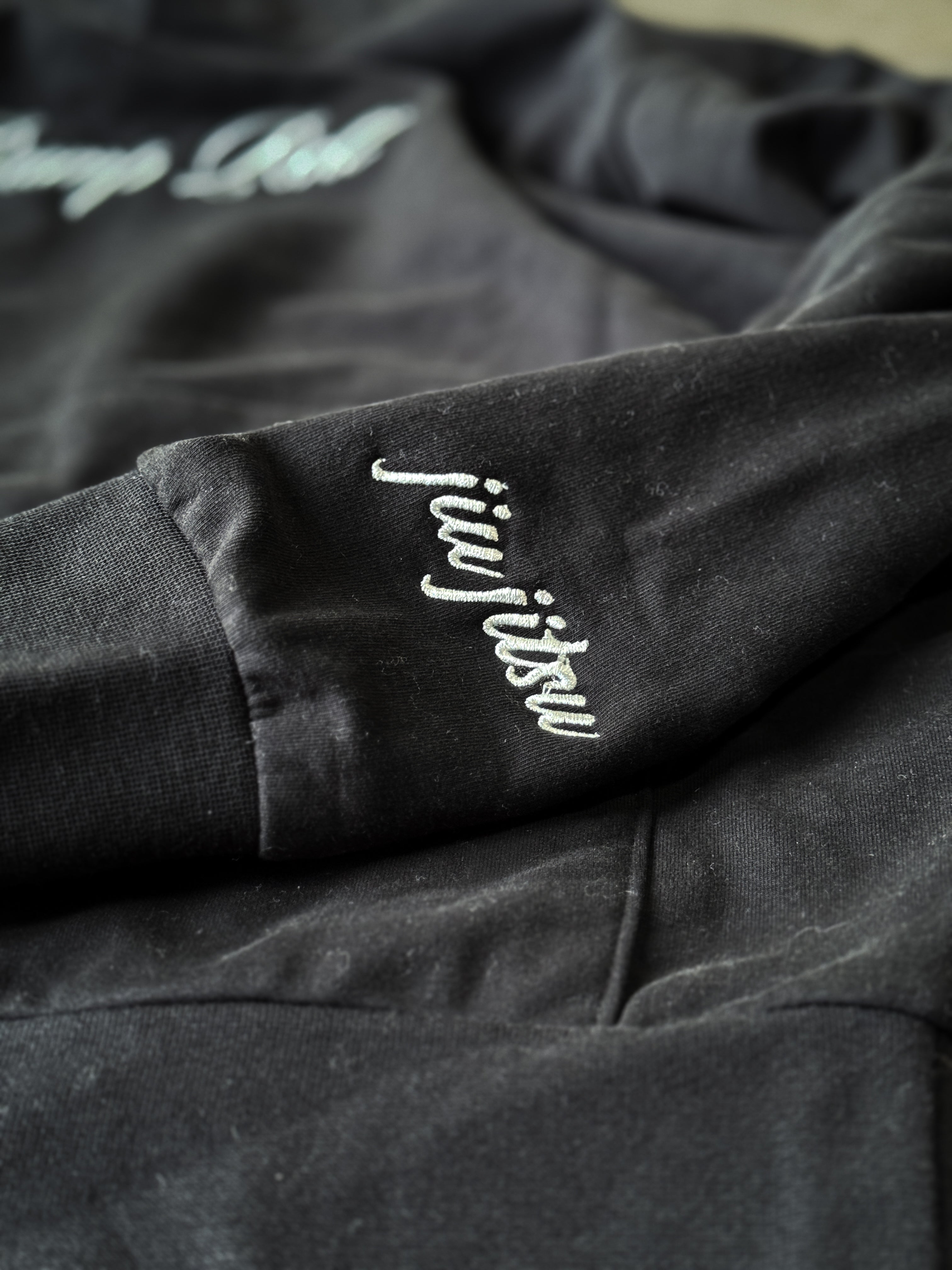 Cursive jiu jitsu embroidery detail on sleeve of SBR Black Butter Hoodie, subtle BJJ identifier