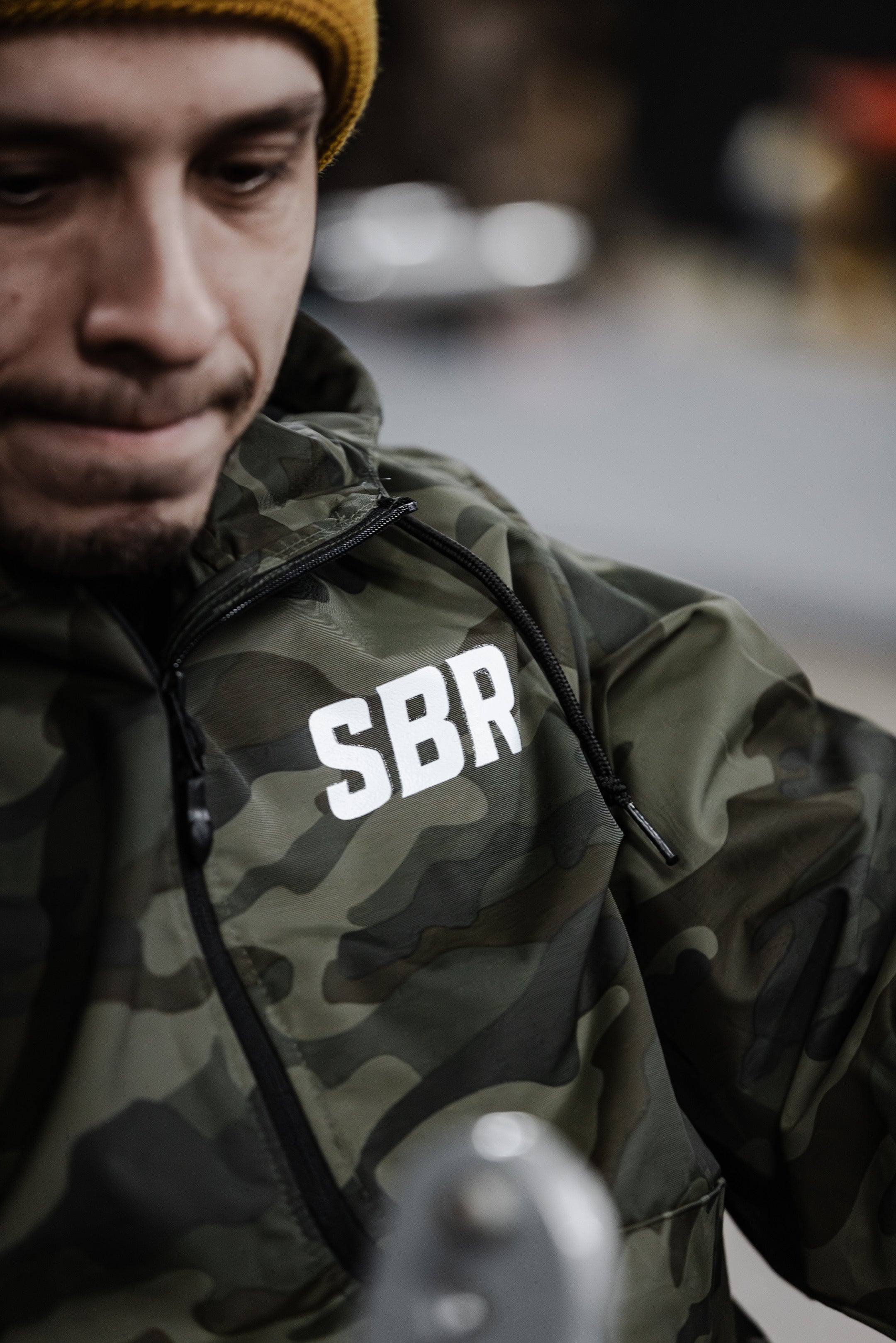 Close-up of SBR Camo Windbreaker showing half-zip pullover design and white SBR chest logo in green camouflage
