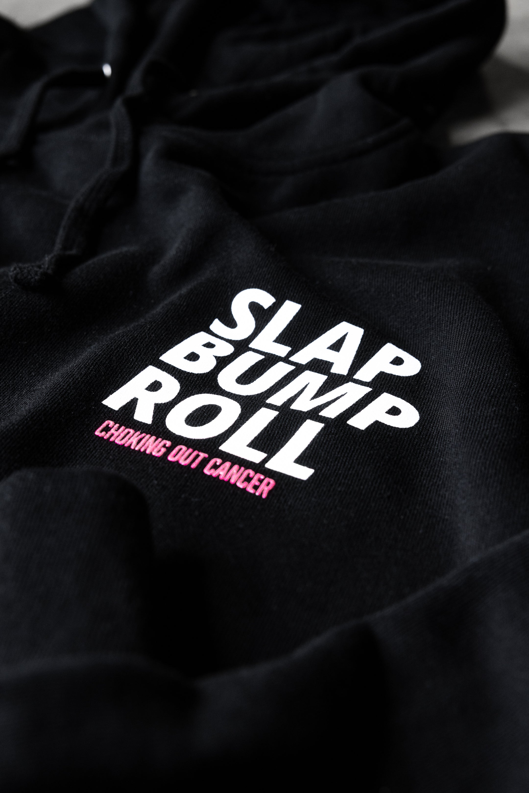 SLAP BUMP ROLL Choking Out Cancer chest print in white and pink on SBR awareness hoodie