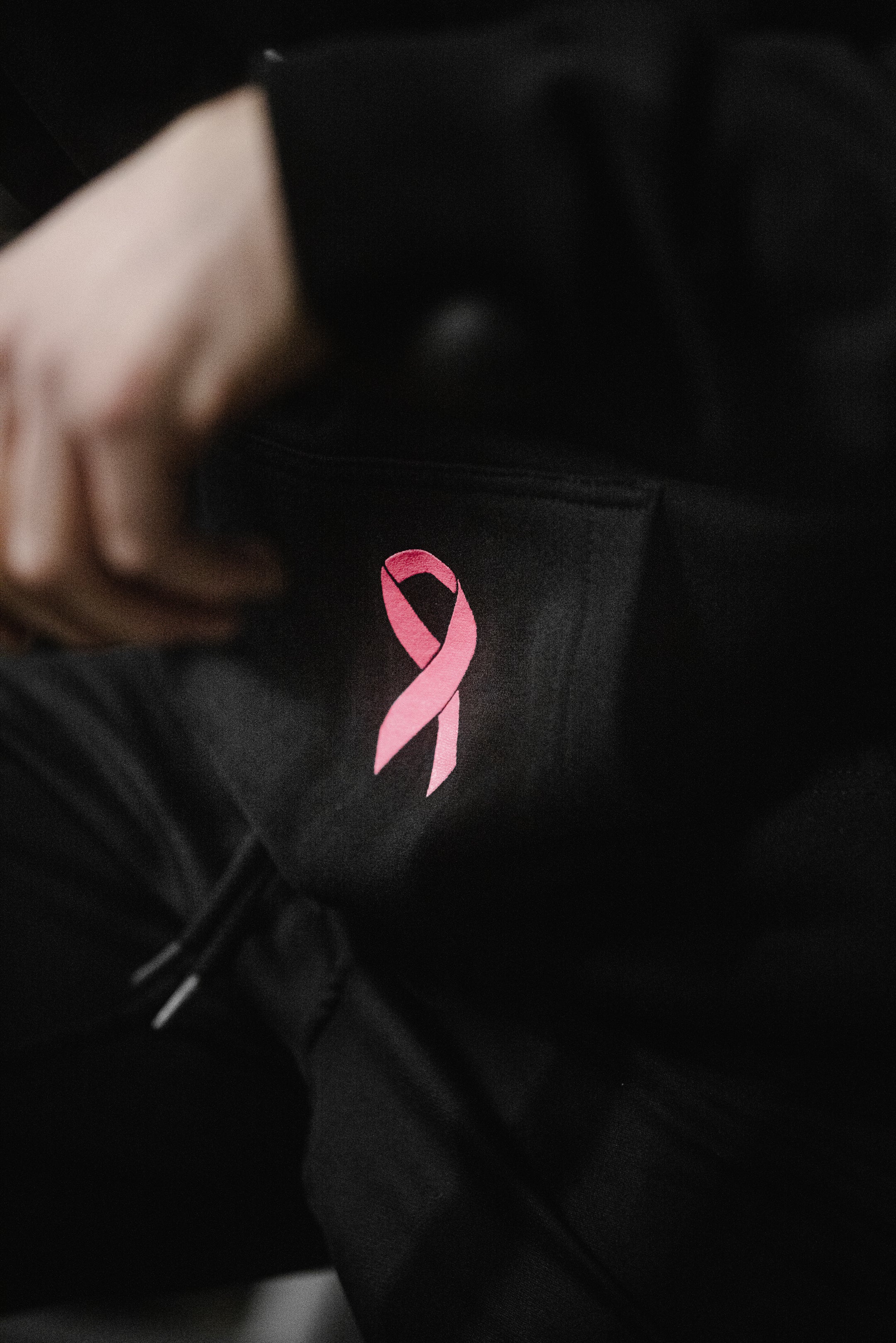 Pink awareness ribbon on front pocket of SBR Choking Out Cancer Hoodie worn