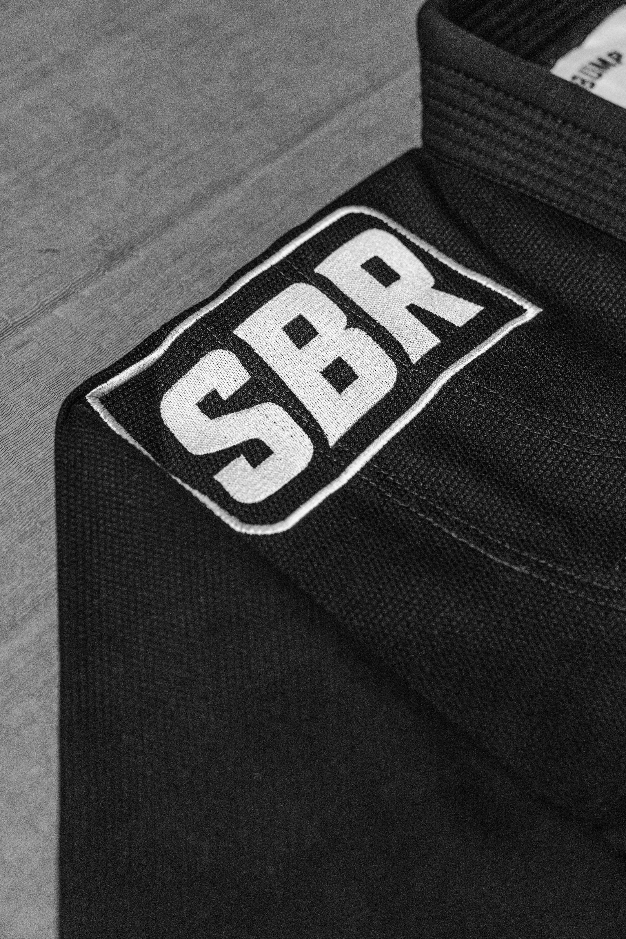 Embroidered SBR box logo patch detail on black SBR Comp Lite BJJ Gi jacket