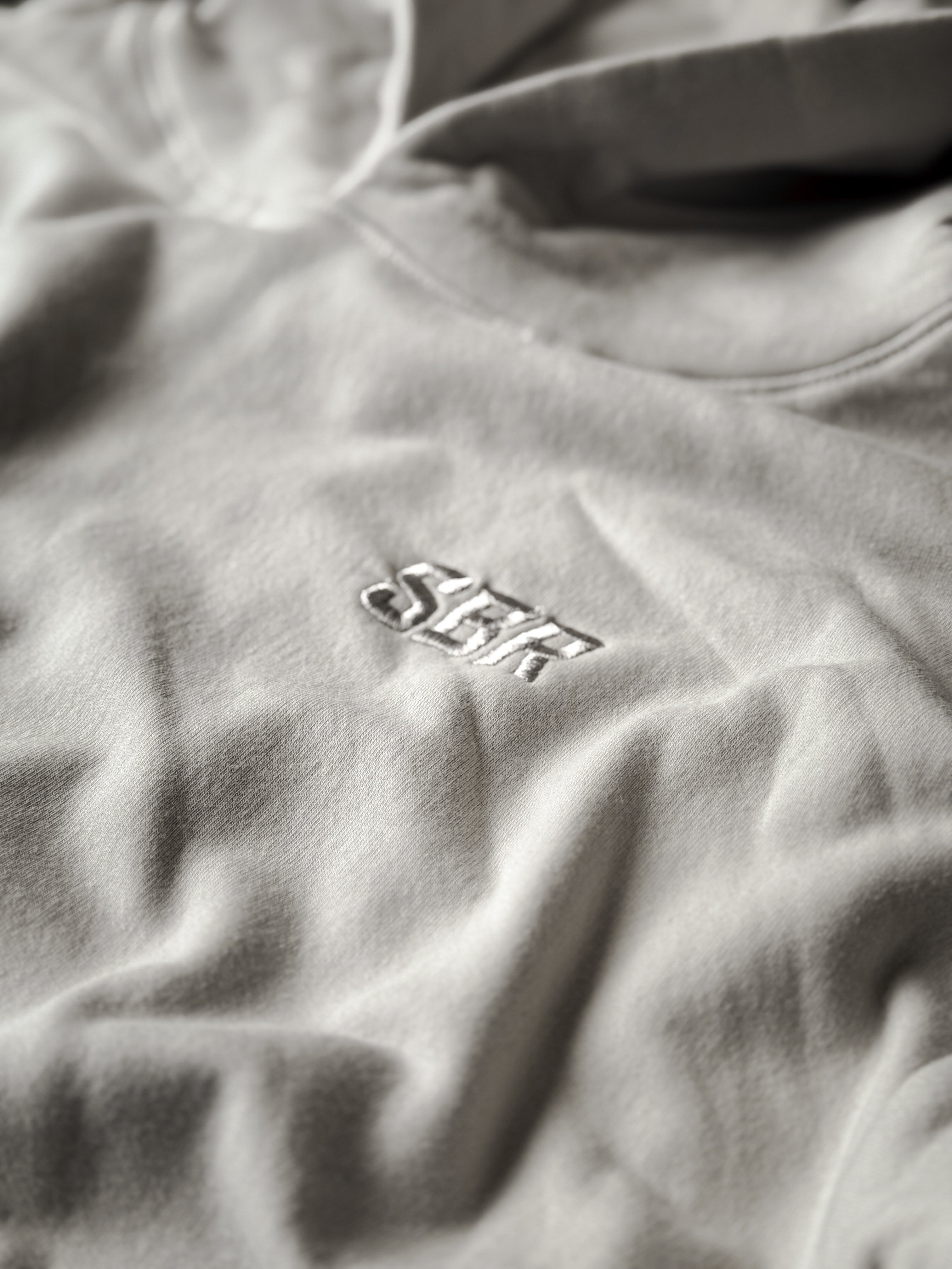 Tonal cream SBR block letter embroidery detail on Cream Butter Hoodie chest, premium minimalist branding