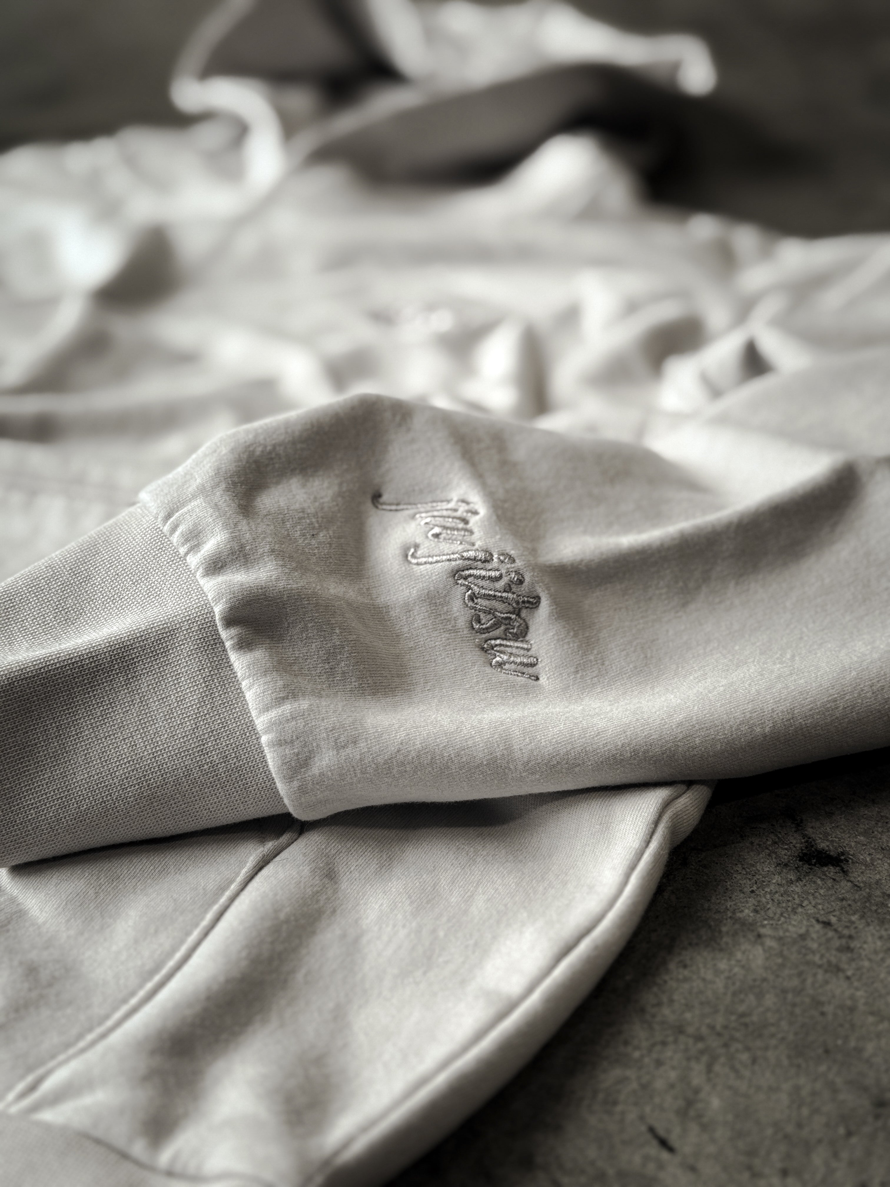Cursive jiu jitsu sleeve embroidery detail on SBR Cream Butter Hoodie in tonal cream thread
