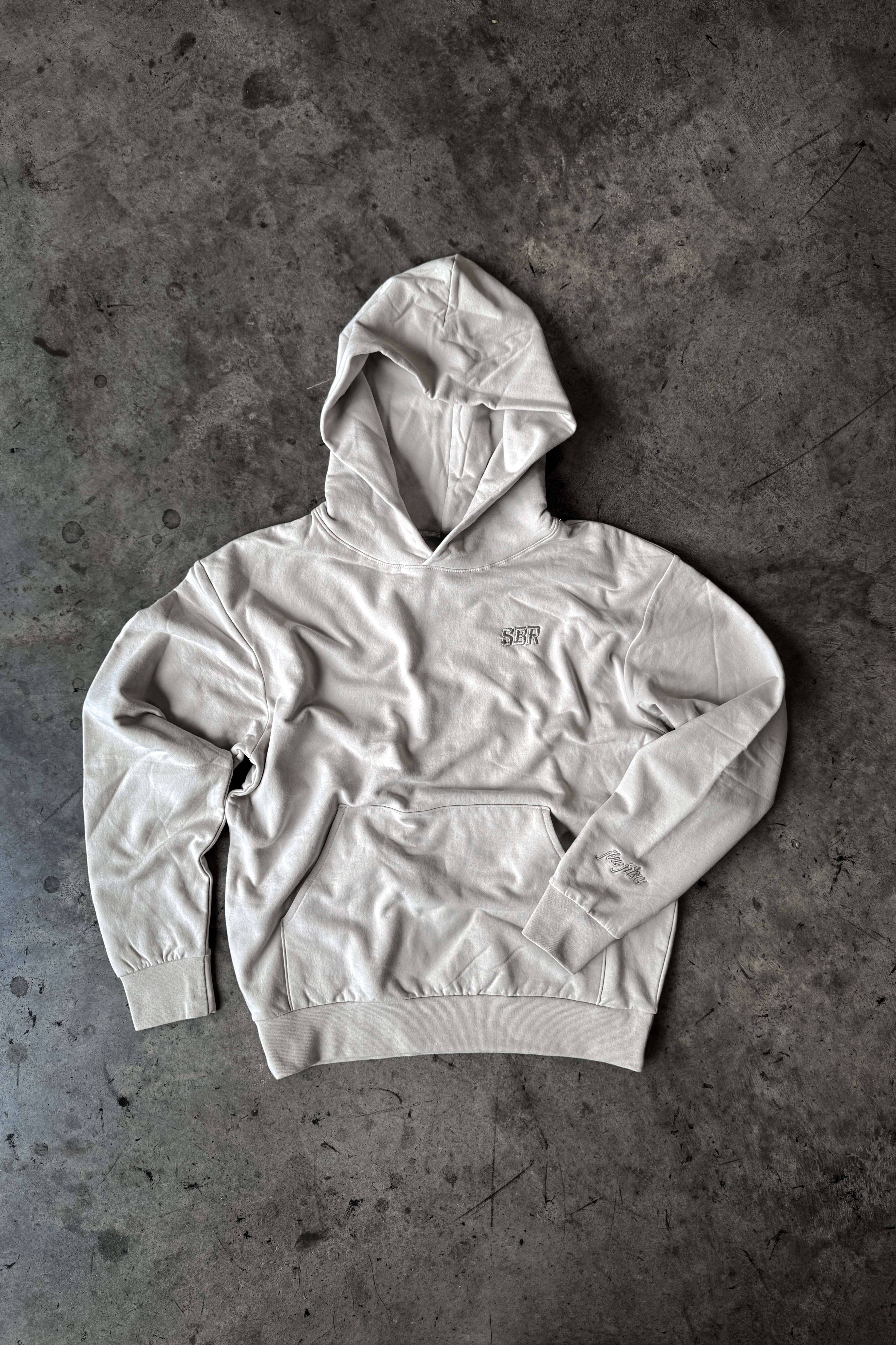 SBR Cream Butter Hoodie flat lay on concrete background, premium tri-blend BJJ lifestyle hoodie by Slap Bump Roll