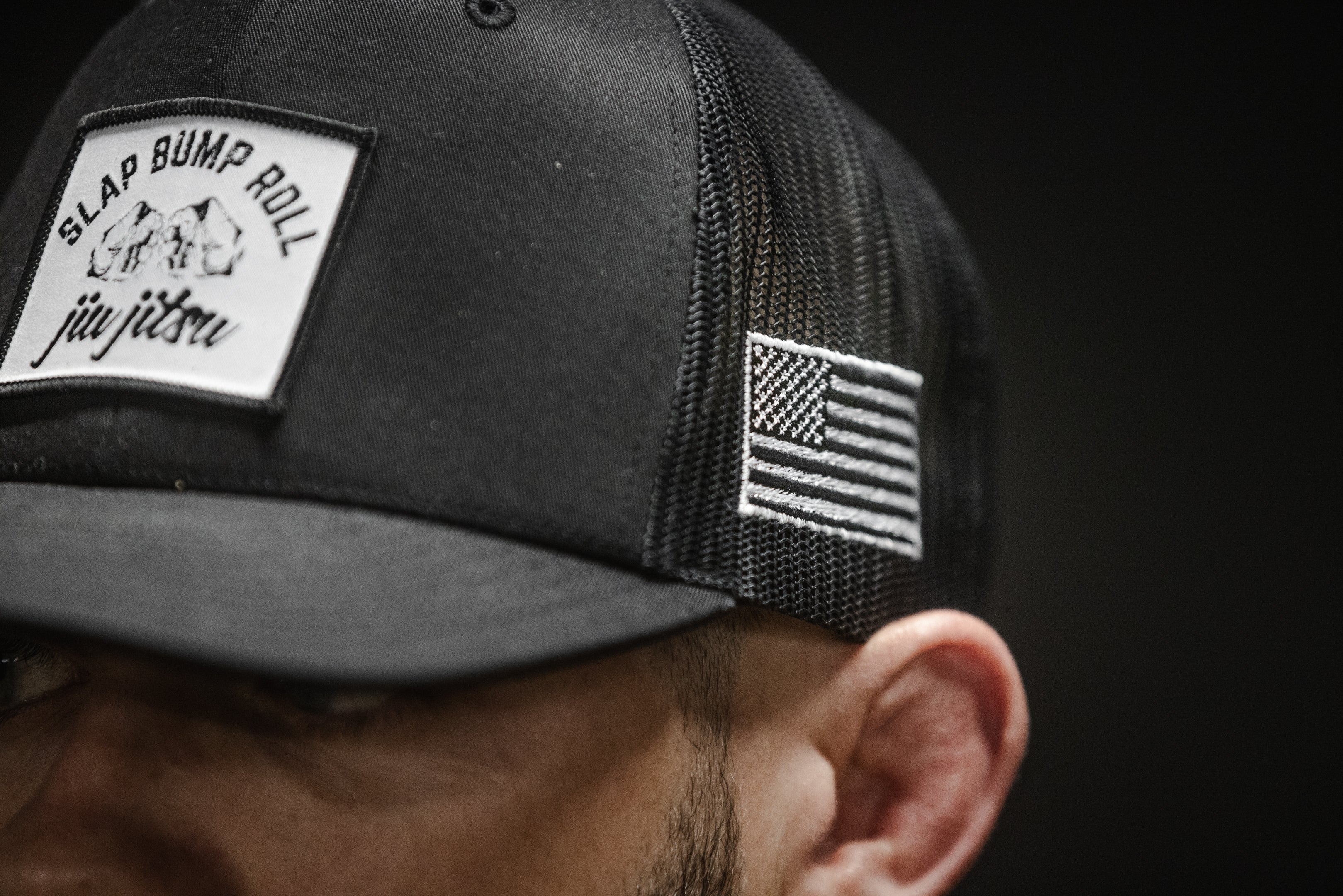 Side view of SBR Jiu Jitsu Trucker Hat showing American flag patch and black mesh back