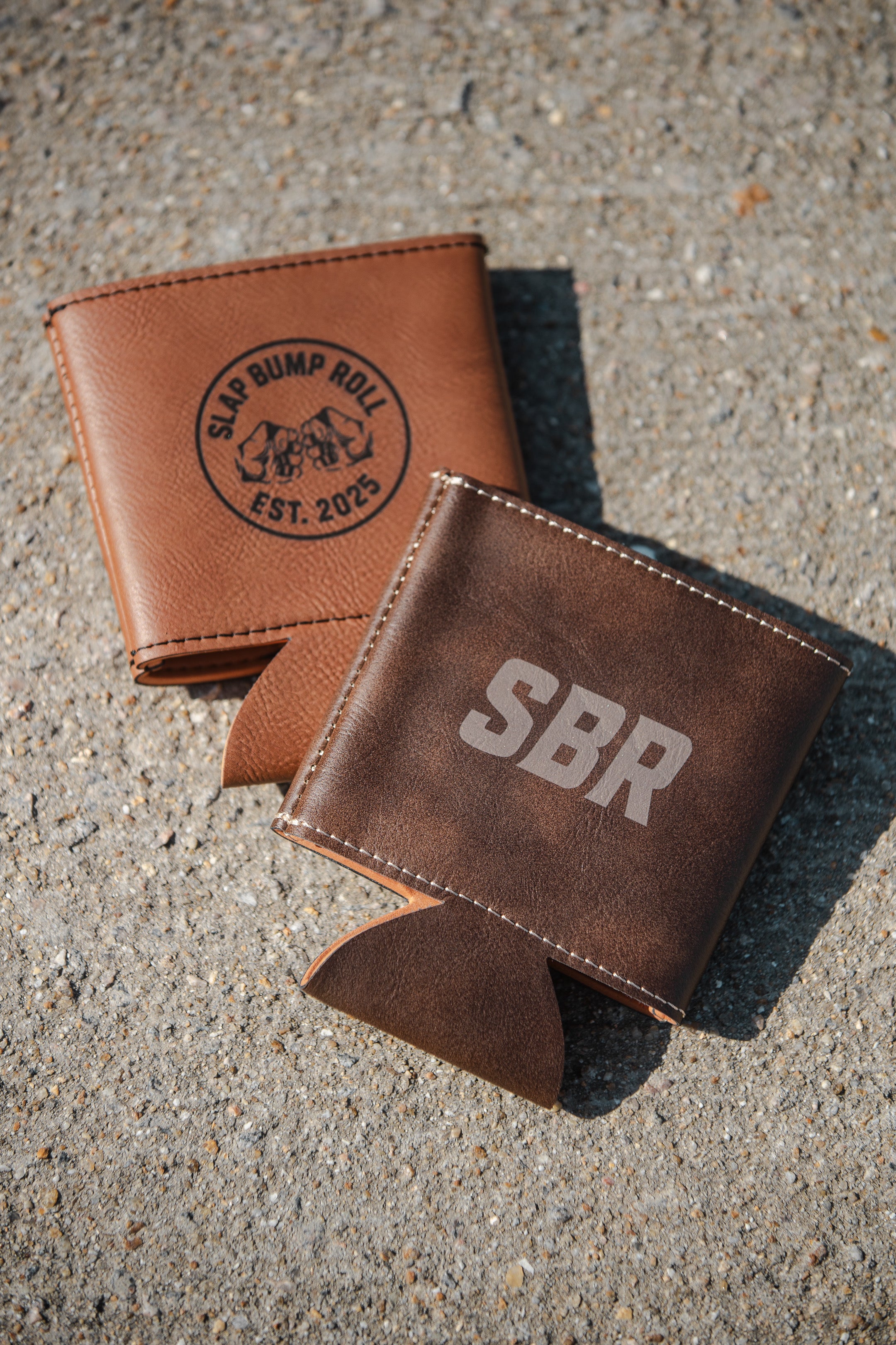 SBR Leatherette Koozies in tan with Slap Bump Roll EST. 2025 circle logo and dark brown with bold SBR lettering