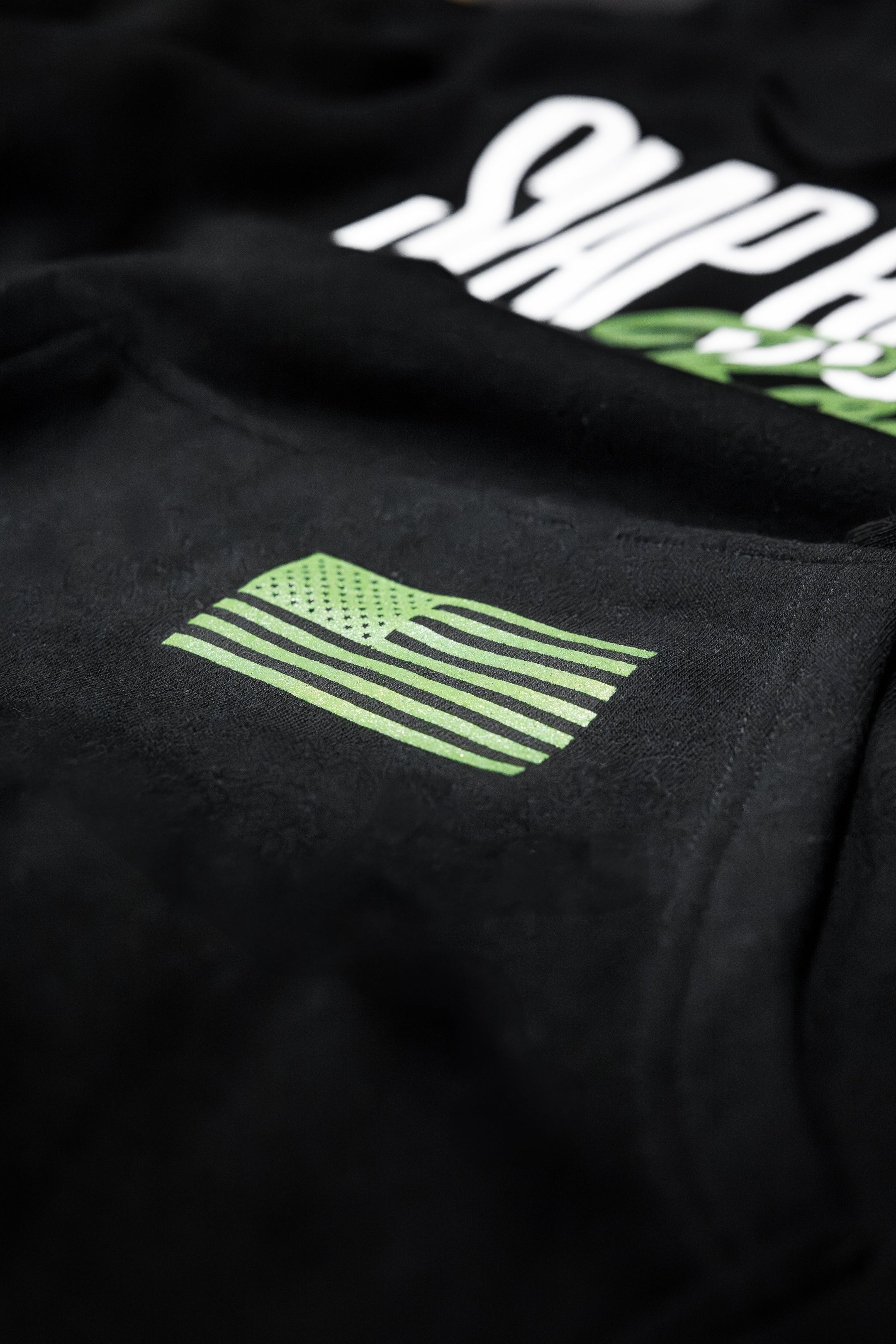 Green American flag screen print on the front pocket of the black Slap Bump Roll midweight BJJ hoodie