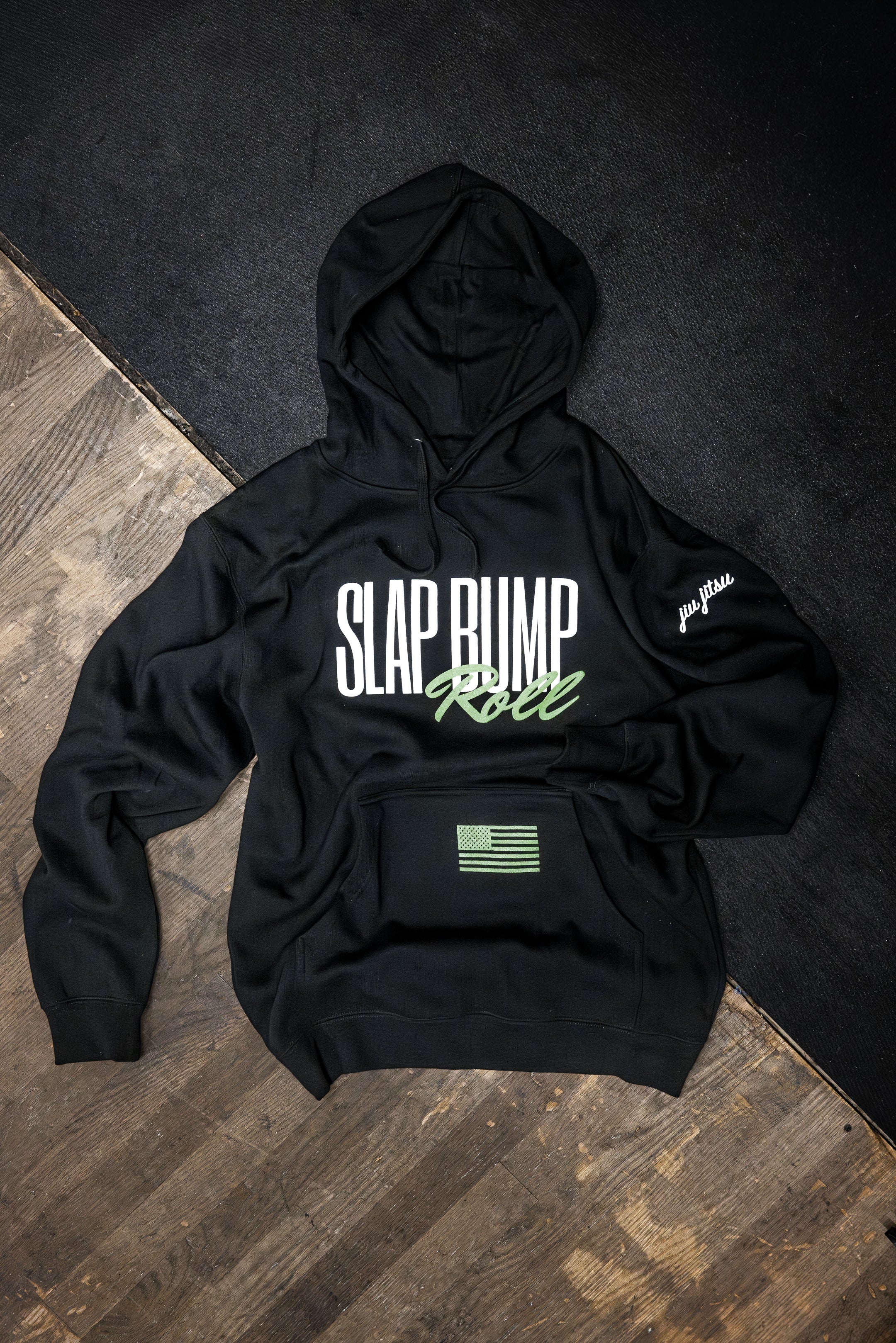 Slap Bump Roll BJJ hoodie in black with white and green SLAP BUMP ROLL wordmark, green flag pocket print, jiu jitsu sleeve